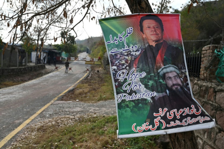 A poster with a picture of Pakistan's former prime minister Imran Khan (top) reading "Revenge of oppression with vote" hangs on a tree outside his residence guarded police in the Banigala area of Islamabad on February 1, 2024