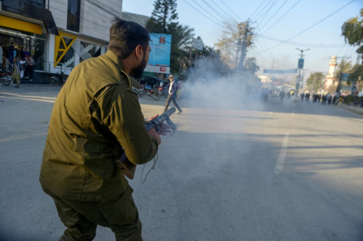 A policeman fires tear gas to disperse supporters of Imran Khan's Pakistan Tehreek-e-Insaf party in Rawalpindi as they protest against the alleged vote rigging in last week's election