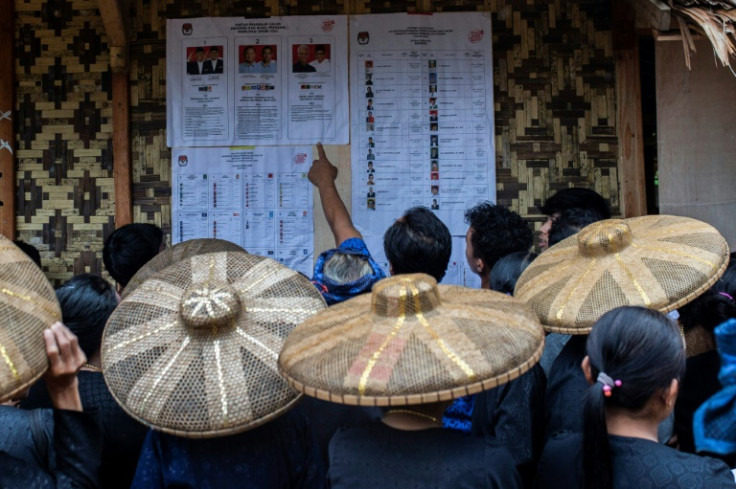 Members of the Baduy tribe in western Java that largely shuns technology and the trappings of modern life check the list of candidates before voting in Kanekes village, Lebak, Banten province