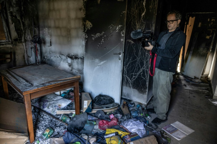 A volunteer with "Edut 710" films a burnt house at Kibbutz Nirim