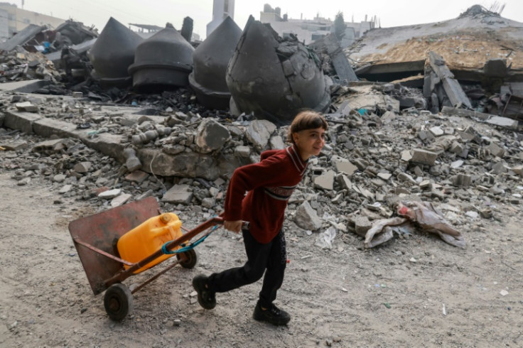 A child carries a container of water past the rubble of Al-Faruq mosque, levelled by Israeli bombardment in Rafah