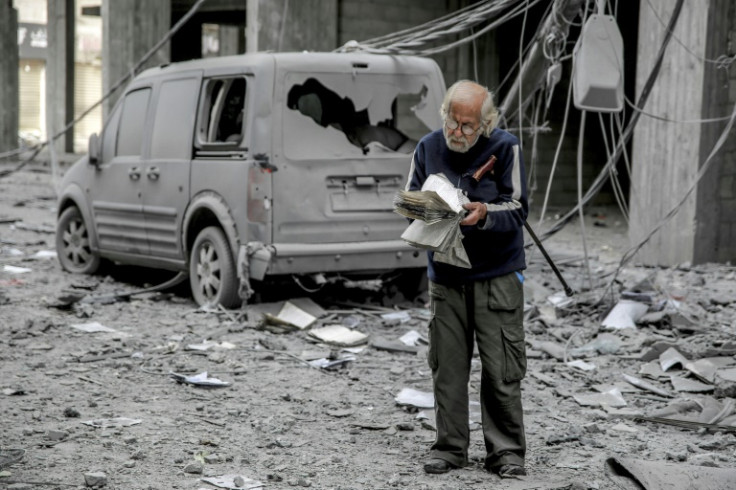 A Palestinian man reads a book in a Gaza City street damaged by Israeli bombardment