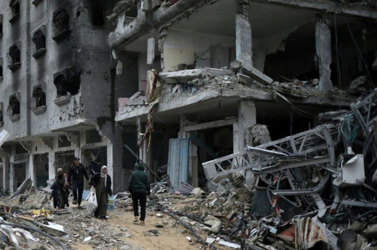 Palestinians walk past buildings gutted by Israeli bombing in the south Gaza city of Khan Yunis