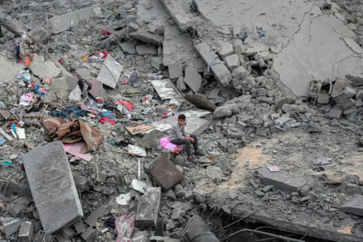 A boy sits among the rubble and scattered belongings of a home was destroyed in an Israeli strike in Deir el-Balah in the central Gaza Strip