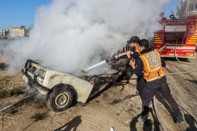 Palestinian Civil Defence members extinguish a burning car after an Israeli bombardment in Rafah in the southern Gaza