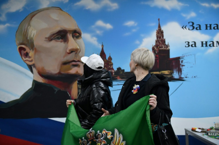 Women pose in front of a mural depicting Russian President Vladimir Putin in a local school in Donetsk, Russian-controlled Ukraine