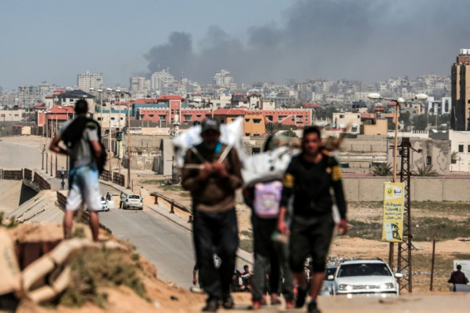 People flee as smoke rises above buildings near the Al-Shifa hospital compound during an Israeli bombardment in Gaza City