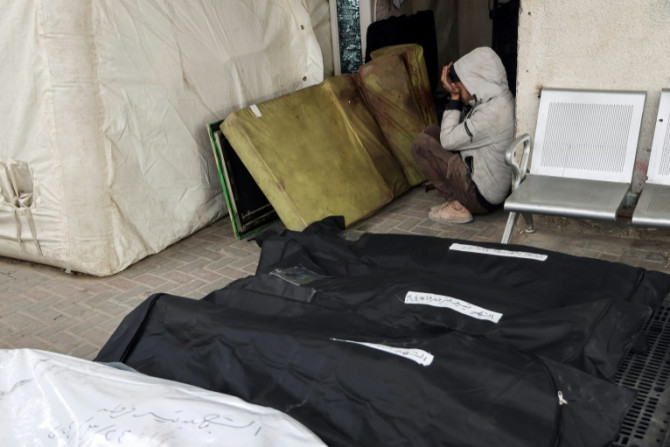 A Palestinian boy sits between a blood-stained mattress and body bags at Rafah's Al-Najjar hospital