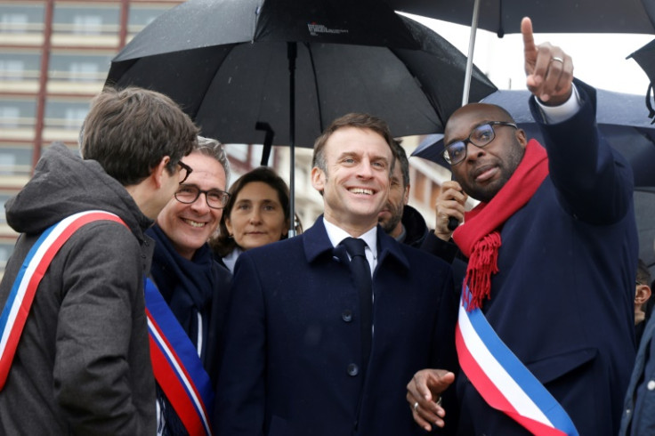 Mohamed Gnabaly (R) shows French President Emmanuel Macron around the Olympic Village