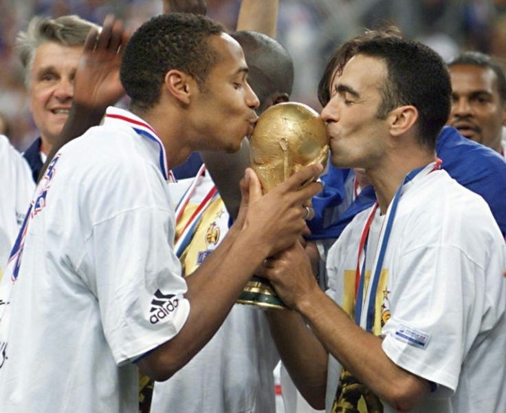 French football legend Thierry Henry (L) and Youri Djorkaeff kiss the World Cup trophy after France won it at Stade de France in 1998