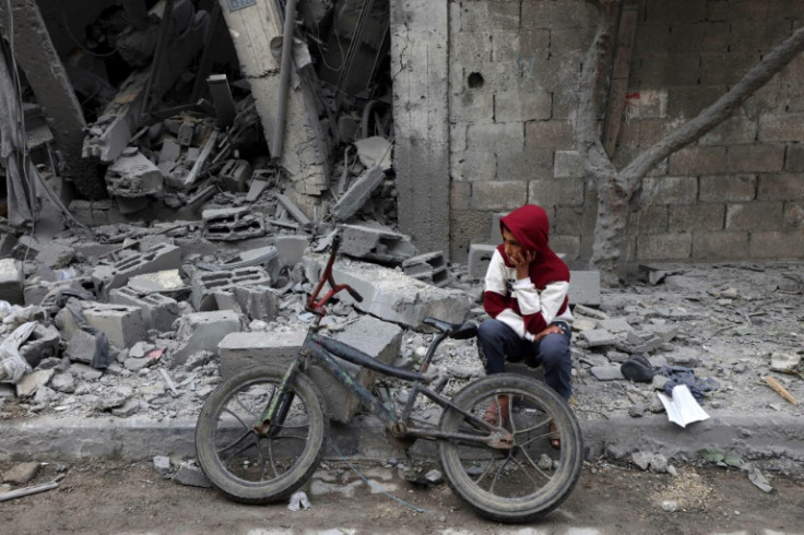 A Palestinian boy sits next to his bicycle in front of a building hit by overnight Israeli bombardment in Rafah in the southern Gaza Strip on March 24, 2024