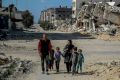 A Palestinian family walk past buildings destroyed in  Gaza City, where the UN has warned that famine is imminent without a major intervention