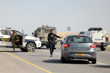 Israeli security forces stop vehicles on a road in the occupied West Bank after a shooting attack which medics and the army said wounded three people