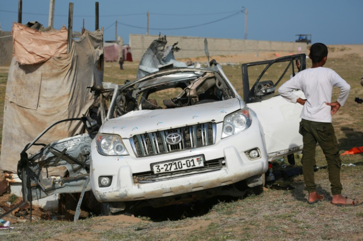 People gather around a car used by US-based aid group World Central Kitchen that was hit by a strike in Deir al-Balah in the central Gaza Strip