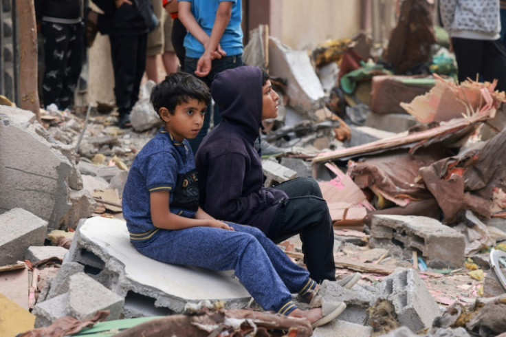 Palestinian boys sit on building rubble following overnight Israeli bombardment in Rafah in the southern Gaza Strip