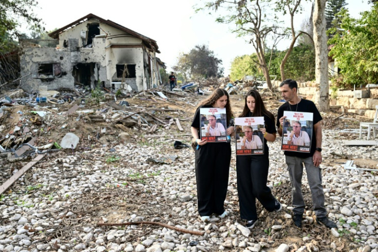 (FILES) Relatives of Ohad ben Ami, 65, an Israeli hostage held in the Gaza Strip since the October 7 attack by Hamas, pose for a picture with his portrait during a visit to kibbutz Beeri in southern Israel near the border with Gaza