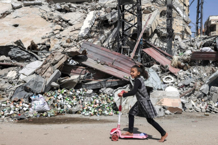 A girl rides a scooter past the rubble of a destroyed building in Rafah in the southern Gaza Strip on April 5, 2024
