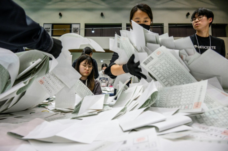 Election officials sort through ballots at a counting station in Seoul