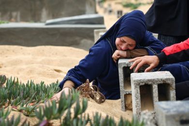 A woman cries over a grave at a makeshit cemetery in Rafah in the southern Gaza Strip, on April 10, 2024