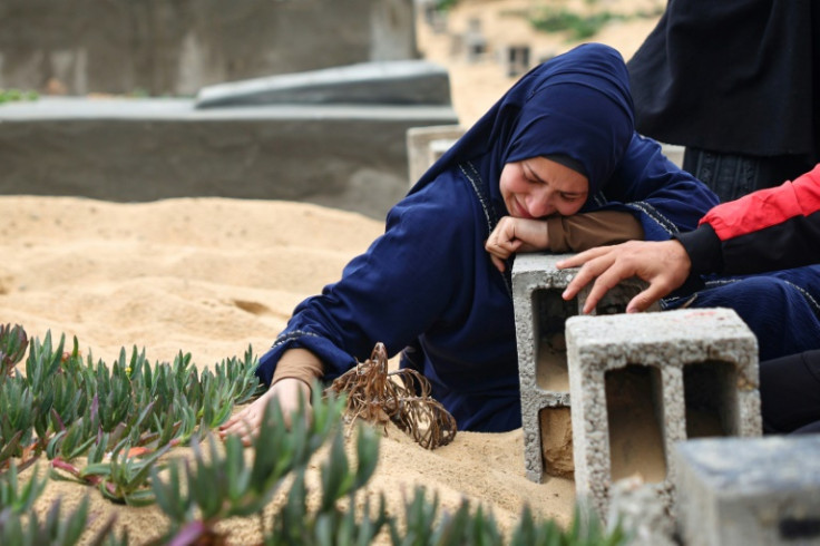 A woman cries over a grave at a makeshit cemetery in Rafah in the southern Gaza Strip, on April 10, 2024