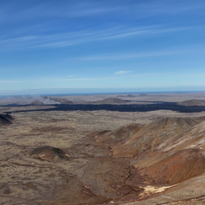 The dark lava field and crater from the current eruption at Sundhnukagigar near Grindavik in southwest Iceland is visible in the background