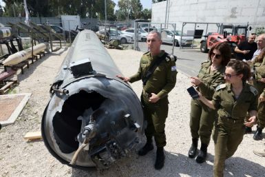 Israeli military personnel next to an Iranian ballistic missile which fell in Israel, at the Julis military base near the southern city of Kiryat Malachi