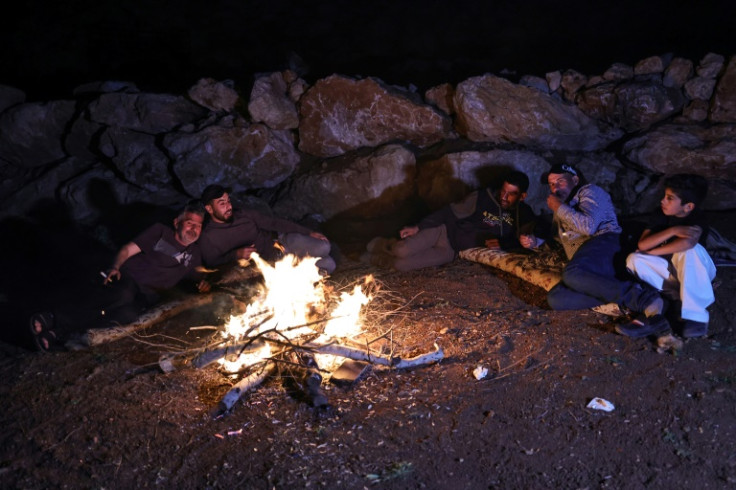 Palestinian men sit around a camp fire as they watch over livestock amid settler attacks in the West Bank