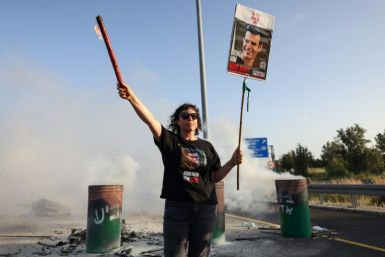 A woman holds a poster of Israeli hostage Dror Or as relatives and supporters of captives held by militants in Gaza block a highway between Tel Aviv and Jerusalem to protest for their release