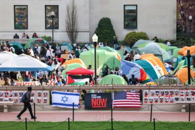A man walks past Israeli and US flags in front of the pro-Palestinian encampment at Columbia University