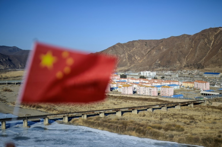 A Chinese flag flaps in the wind with the North Korean city of Namyang in the background across the Tumen river