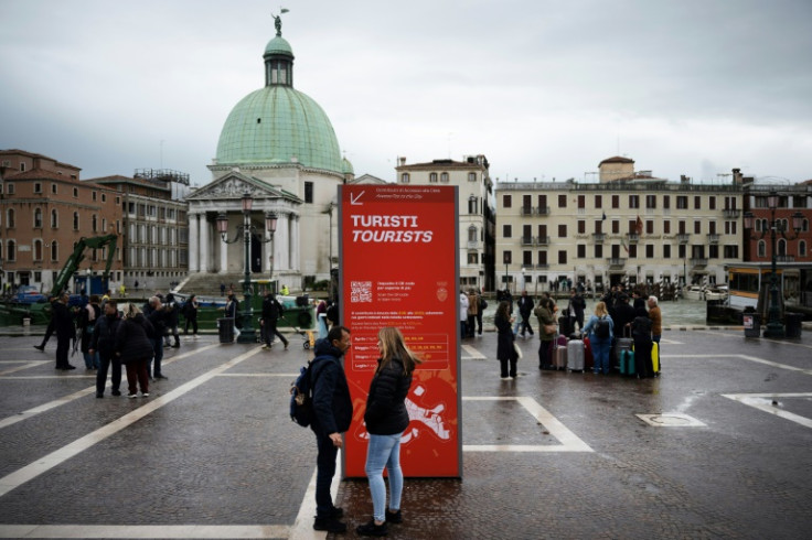 People stand by an information board near Santa Lucia train station on April 24, 2024