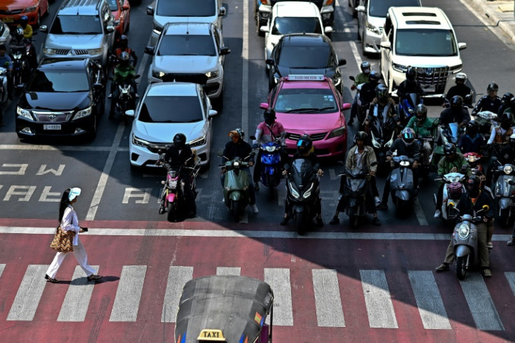 Motorcyclists wait under the shade at a traffic intersection in Bangkok
