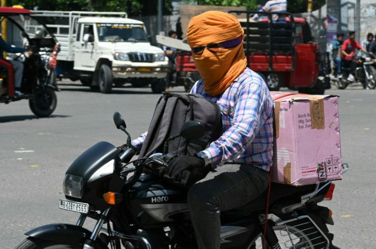 A man on a motorcycle has his face covered with a scarf to shelter from the heat in Amritsar in India