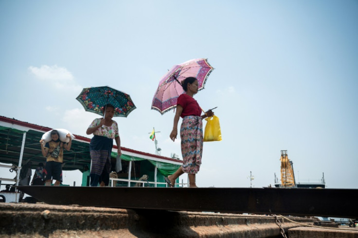 Women walk under umbrellas to shelter from the sun on a hot day in Yangon, as authorities issue extreme heat warnings across South and Southeast Asia