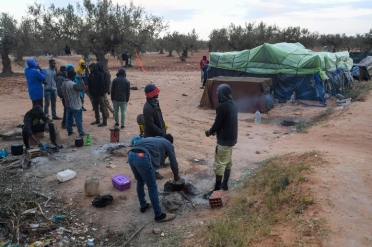 Migrants from sub-Saharan Africa near makeshift shelters among olive trees at El Amra
