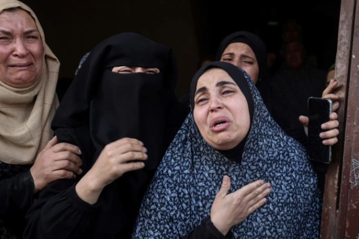 Palestinian women weep as the bodies of wounded and killed relatives are taken away from a residential building that was targeted in overnight bombardment in Rafah