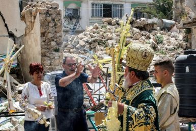 Greek Orthodox Archbishop Alexios of Tiberias throws cross-shaped palm fronds to bless worshippers from Gaza's Christian minority in a procession during the Palm Sunday service to mark the start of Holy Week for Orthodox Christians, in Gaza City