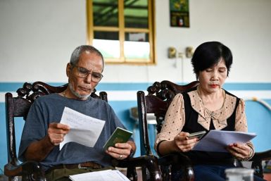 Le Tuan Binh (L), whose father called him Ali, looks through documents at his home in a small village north of Hanoi