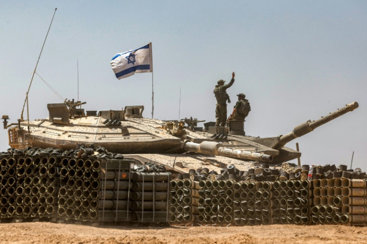 An Israeli army soldier gestures atop the turret of a main battle tank in southern Israel near the Gaza border