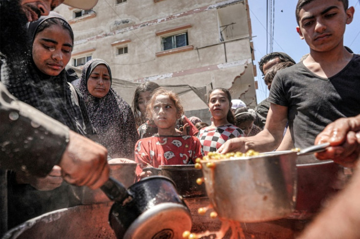 People are handed food portions at a public kitchen in Deir el-Balah in the central Gaza Strip