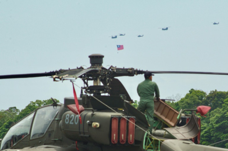 A Taiwanese serviceman maintains a US-made Apache attack helicopter as other helicopters fly Taiwan's flag during a rehearsal ahead of the May 20 presidential inauguration ceremony