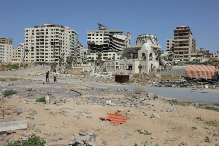 Palestinians walk past damaged and destroyed buildings in Gaza City