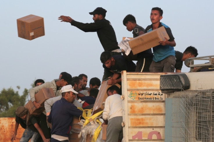 Palestinians take boxes of humanitarian aid after rushing the trucks bringing it from the US-built Trident Pier near Nuseirat in the central Gaza Strip on May 18, 2024