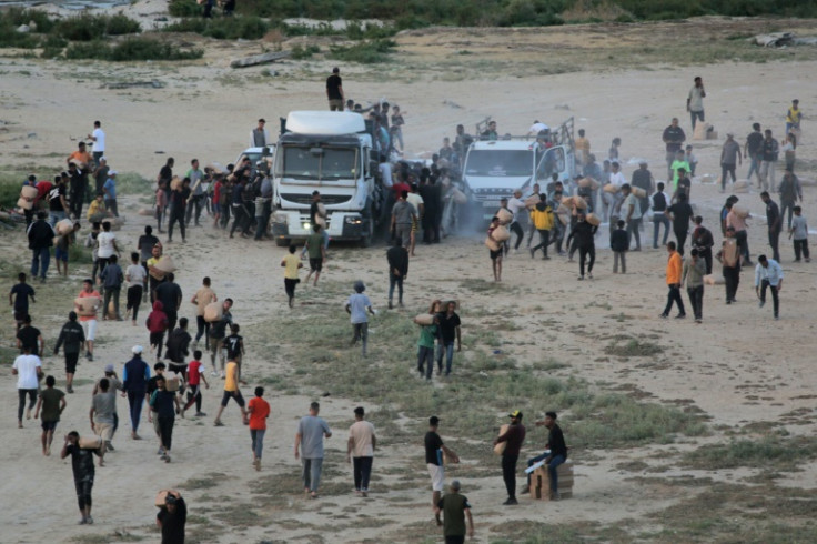 Palestinians rush trucks as they transport international humanitarian aid from the US-built Trident Pier near Nuseirat in the central Gaza Strip on May 18, 2024