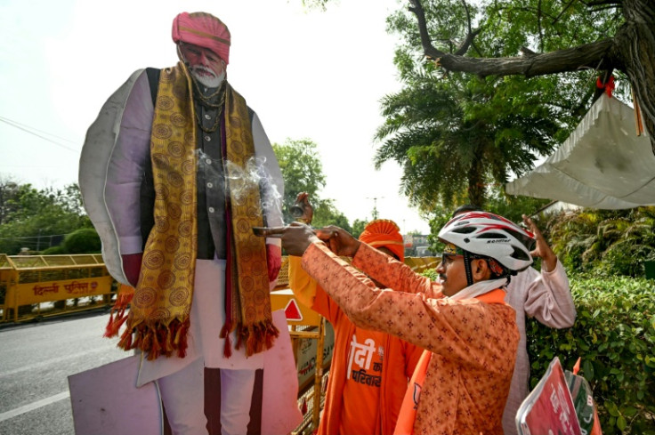 A supporter of India's Prime Minister Narendra Modi performs rituals infront of the leader's cut-out in New Delhi on June 4