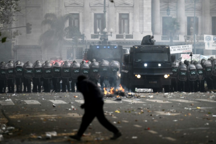 A demonstrator walks in front of formed anti-riot police officers during a protest outside the National Congress in Buenos Aires
