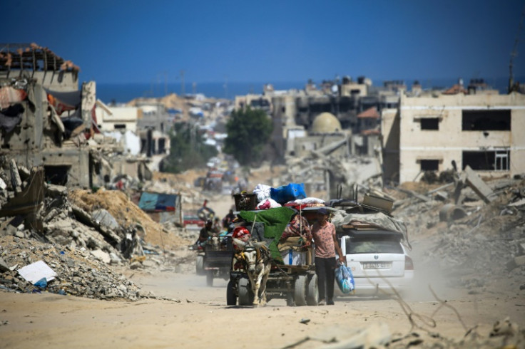 Palestinians walk and drive past buildings destroyed during previous Israeli bombardment in Khan Yunis in the southern Gaza Strip on July 3, 2024