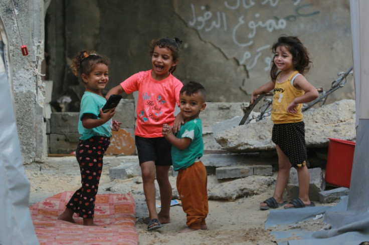 Palestinian children play as they queue to fill containers with water in Khan Yunis in the southern Gaza Strip