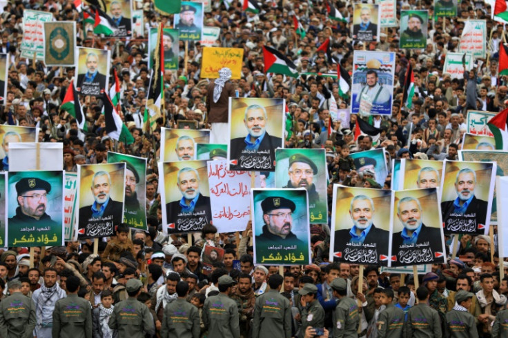 Yemenis wave flags and lift placards of Hezbollah military commander Fuad Shukr and Hamas chief Ismail Haniyeh, both of them slain in strikes blamed on Israel, during a rally in Huthi-controlled Sanaa