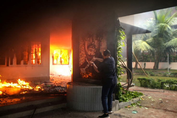 A protester vandalises a portrait of Bangladesh's founding father Sheikh Mujibur Rahman, the father of ousted leader Sheikh Hasina, in a museum